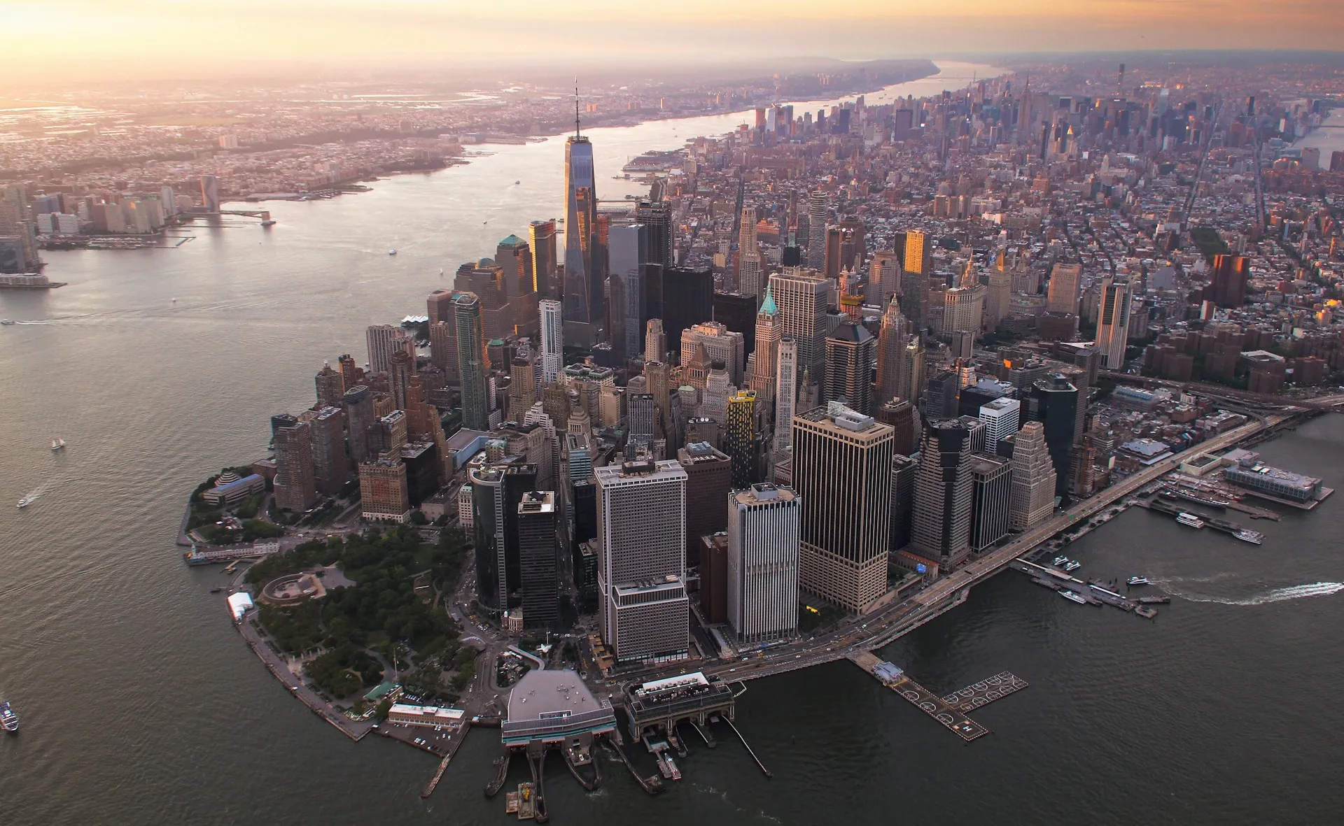 Banks run brokers in every trading centre and link them over the WAN, the same shape a manufacturer needs across plants. Aerial view of a dense financial district skyline on a waterfront peninsula at sunset