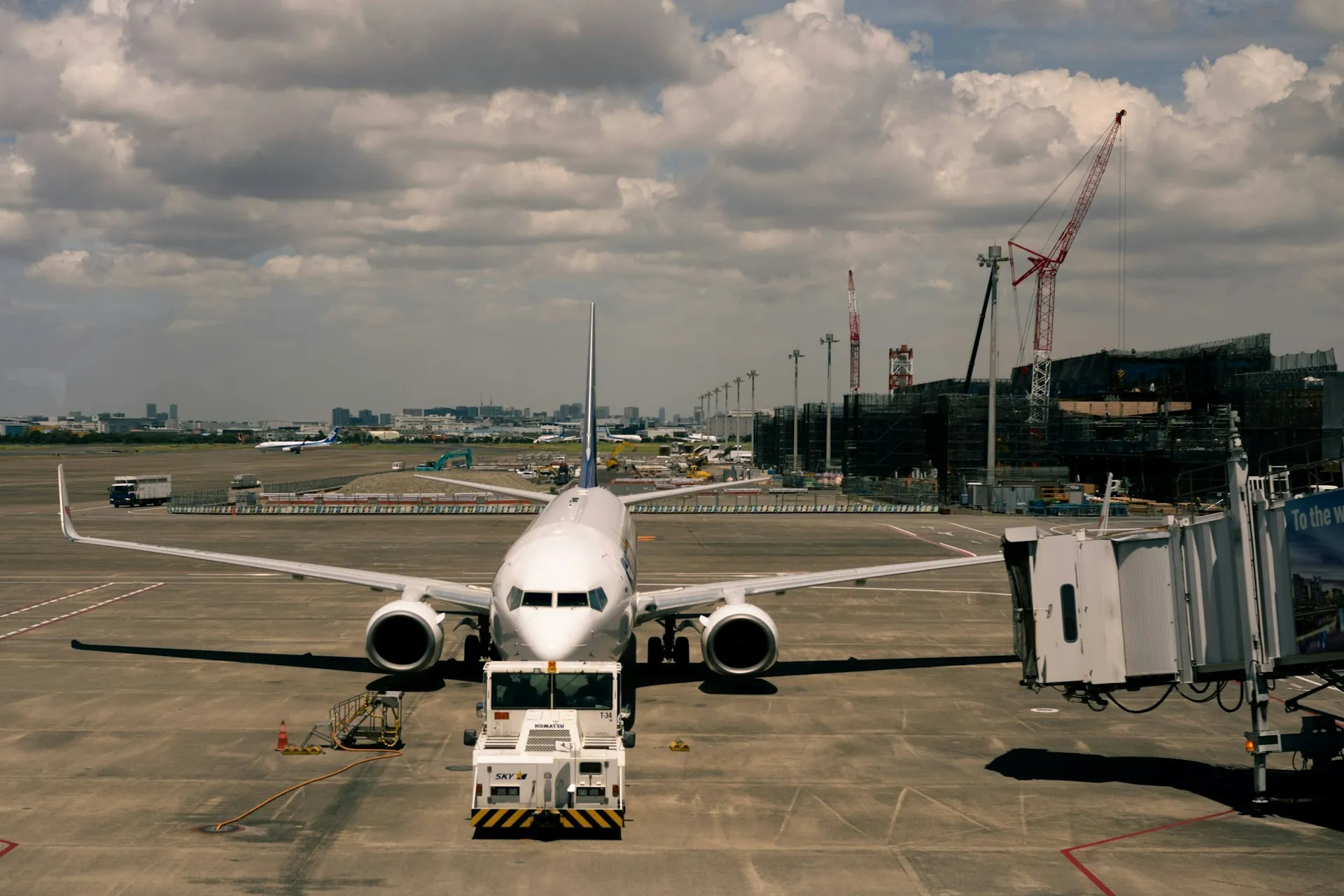 A turnaround only runs on time when every team hears each event as it happens, which is the case for events over polling. Passenger jet facing the camera at a gate beside a jet bridge with a pushback tug in front