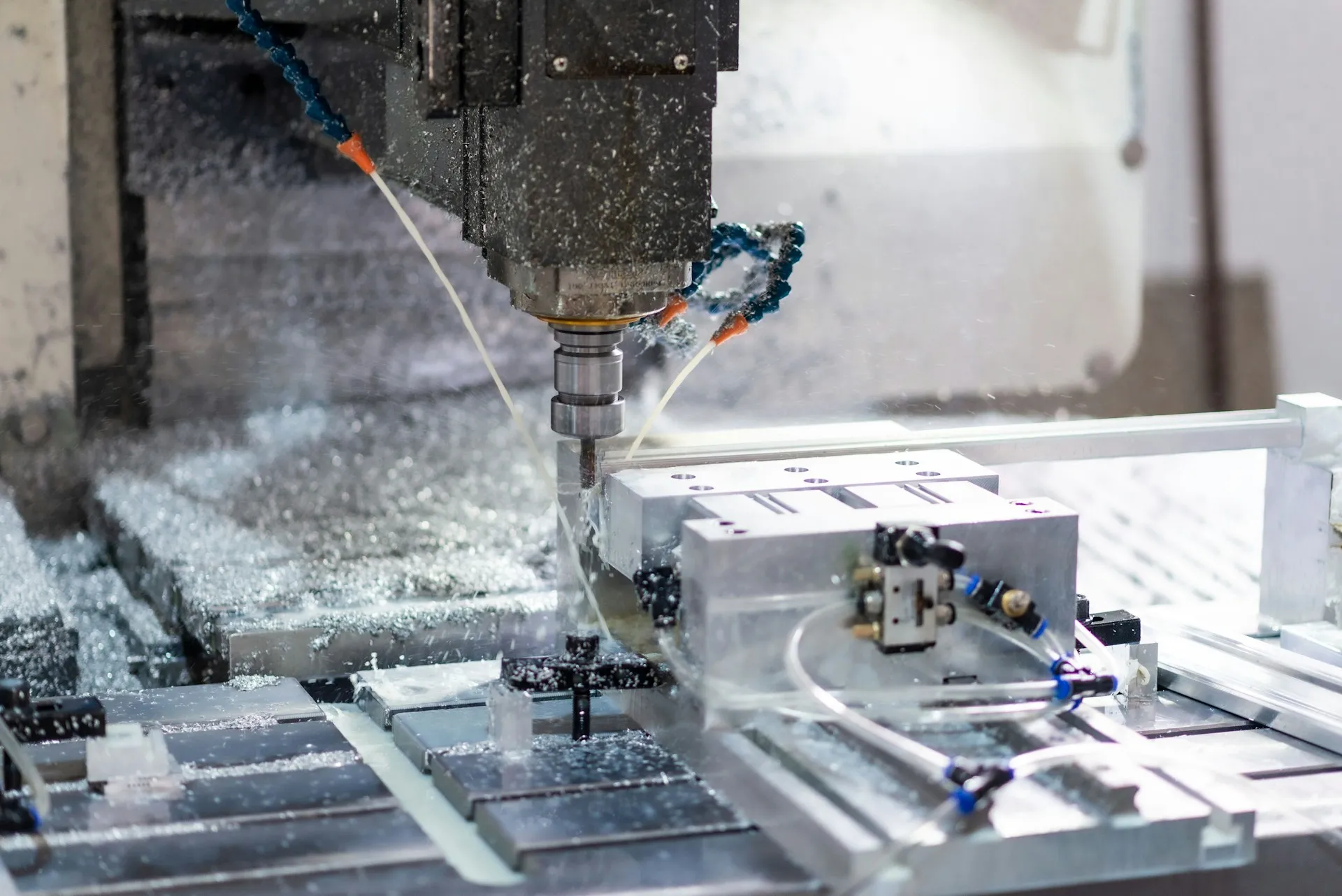 The part program is the visible half of a CNC backup. Offsets, machine data and compensation decide whether the first part after a reload is good. CNC milling spindle cutting an aluminium part held in a fixture, with coolant lines and chips