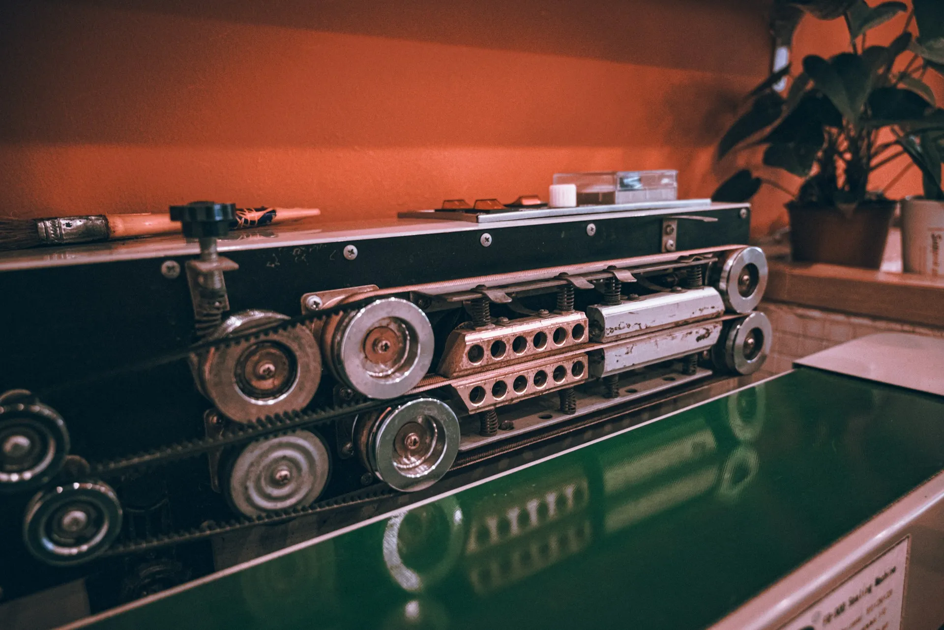 One machine, local I/O, no redundancy: that is CompactLogix territory, and a chassis would add cost without adding anything the machine needs. Compact belt-driven sealing machine with toothed rollers and pulleys on a workbench