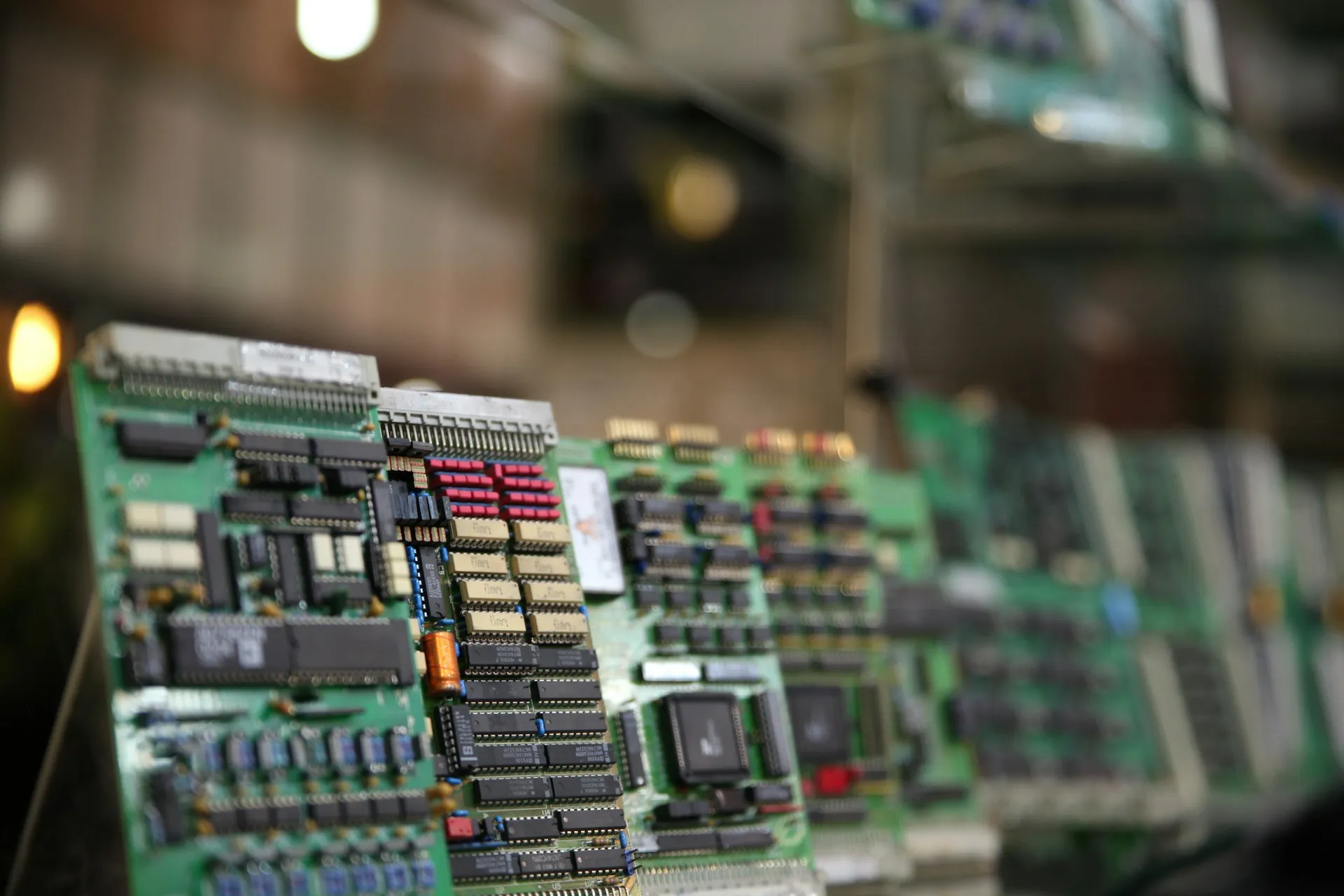 Every pattern starts at hardware like this. Ignition and HighByte decide how the data leaves the controller and what shape it has; Solace decides where it goes after that. Row of green controller circuit cards seated in a rack, shot in shallow focus