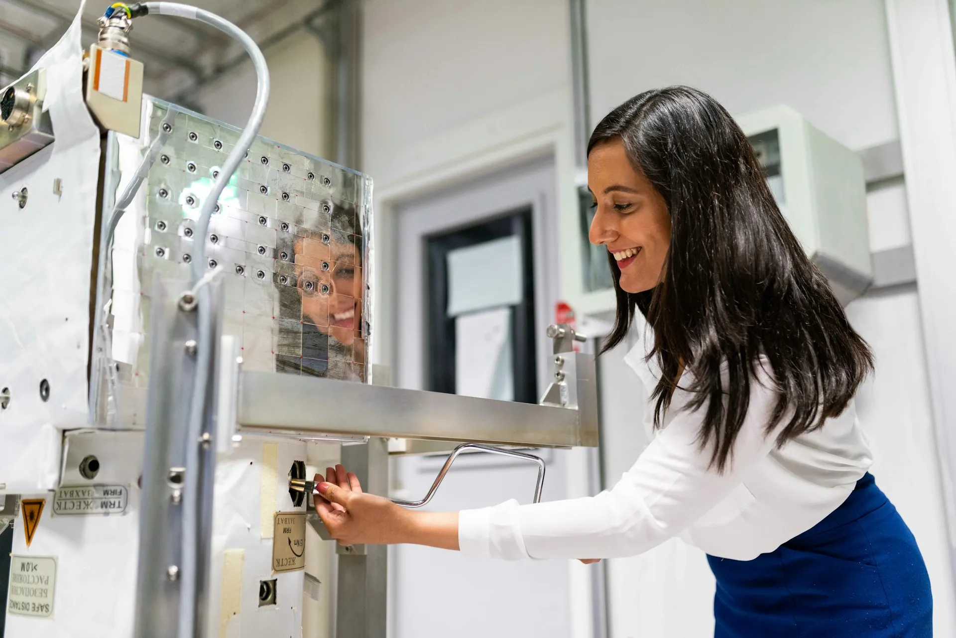 Engineer leaning into a steel test fixture to check a fitting on instrumented hardware in a clean lab