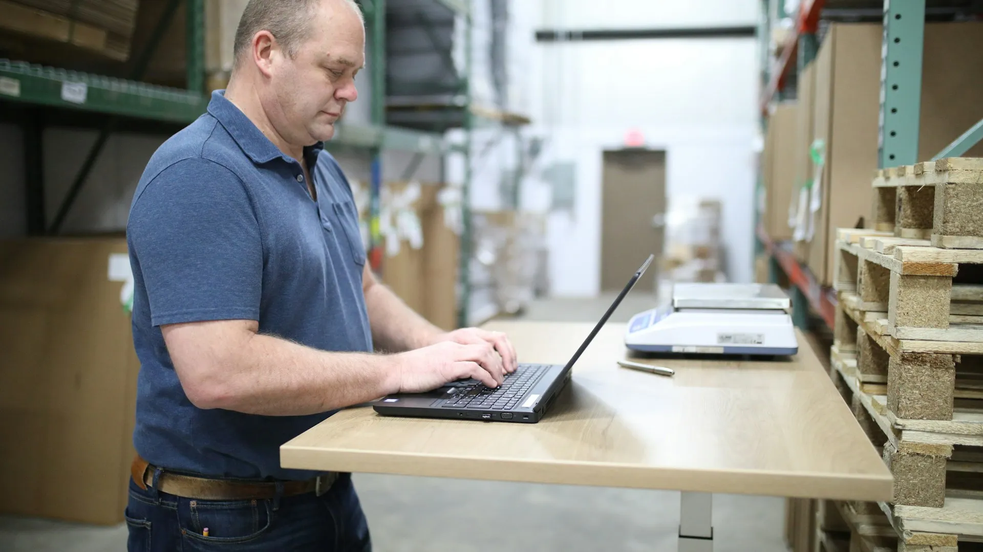 The shortlist comes from your own asset list, checked device by device against each vendor's current matrix, not from the vendors' logo walls. Engineer in a polo shirt typing on a laptop at a standing desk in a warehouse aisle