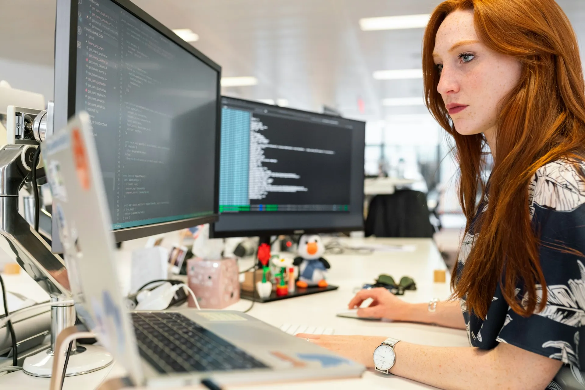 Most of the platform is configuration and code: topics, queues, connectors and schemas that a team designs, reviews and versions like any other software. Engineer at a desk studying code and terminal output across two large monitors