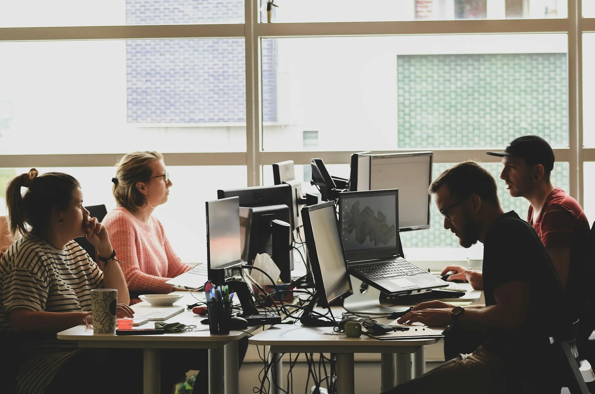 The choice follows the team as much as the plant: engineers who want to work in a browser against a shared history, or a maintenance organisation protecting a large installed base it did not write. Engineering team working at several monitors and a laptop beside a bright office window