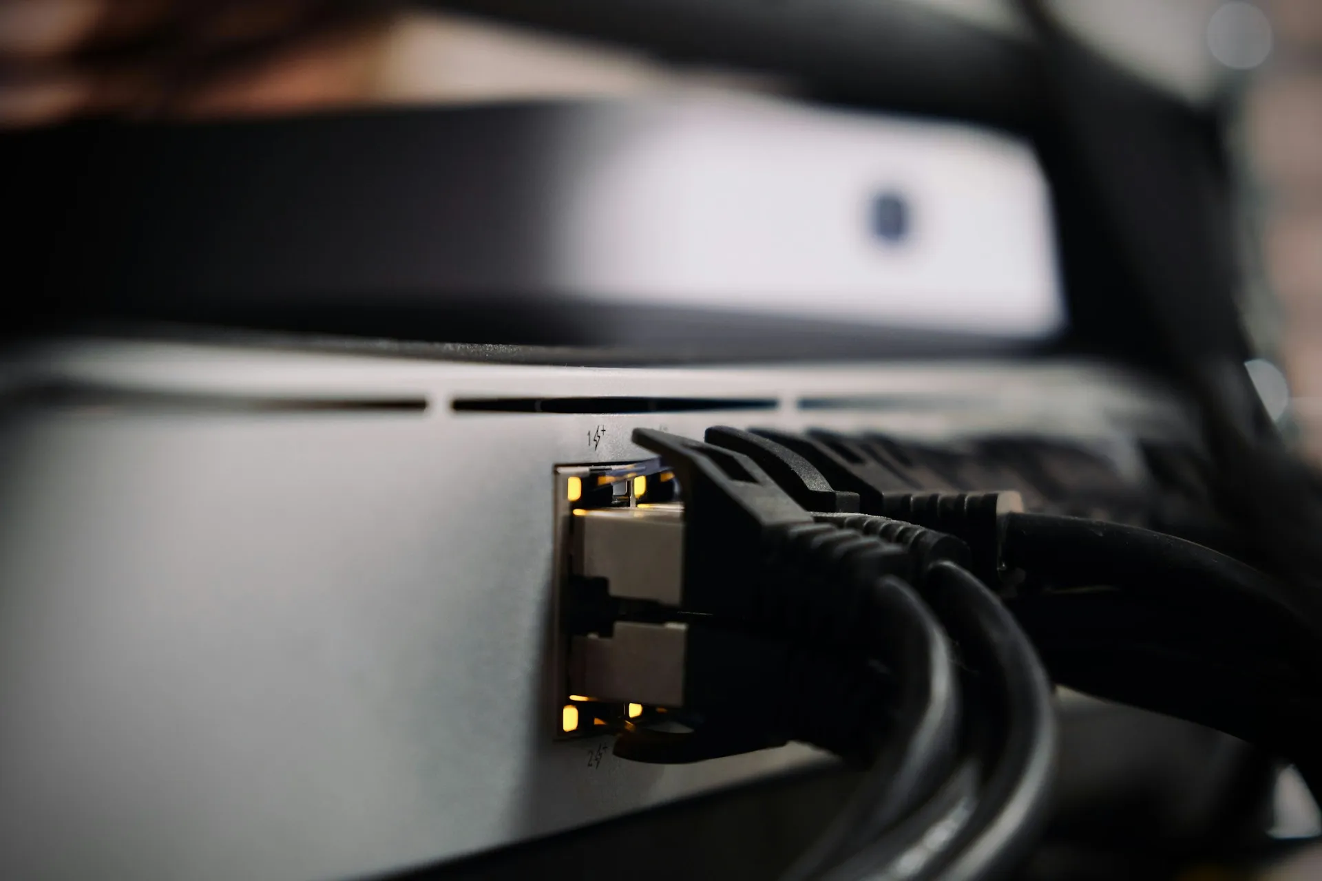 A protocol is an agreed plug shape. Every MCP server you connect is another live connection into your systems, and deserves the same scrutiny as a new network port. Close-up of black ethernet cables plugged into the lit ports on the back of a network device