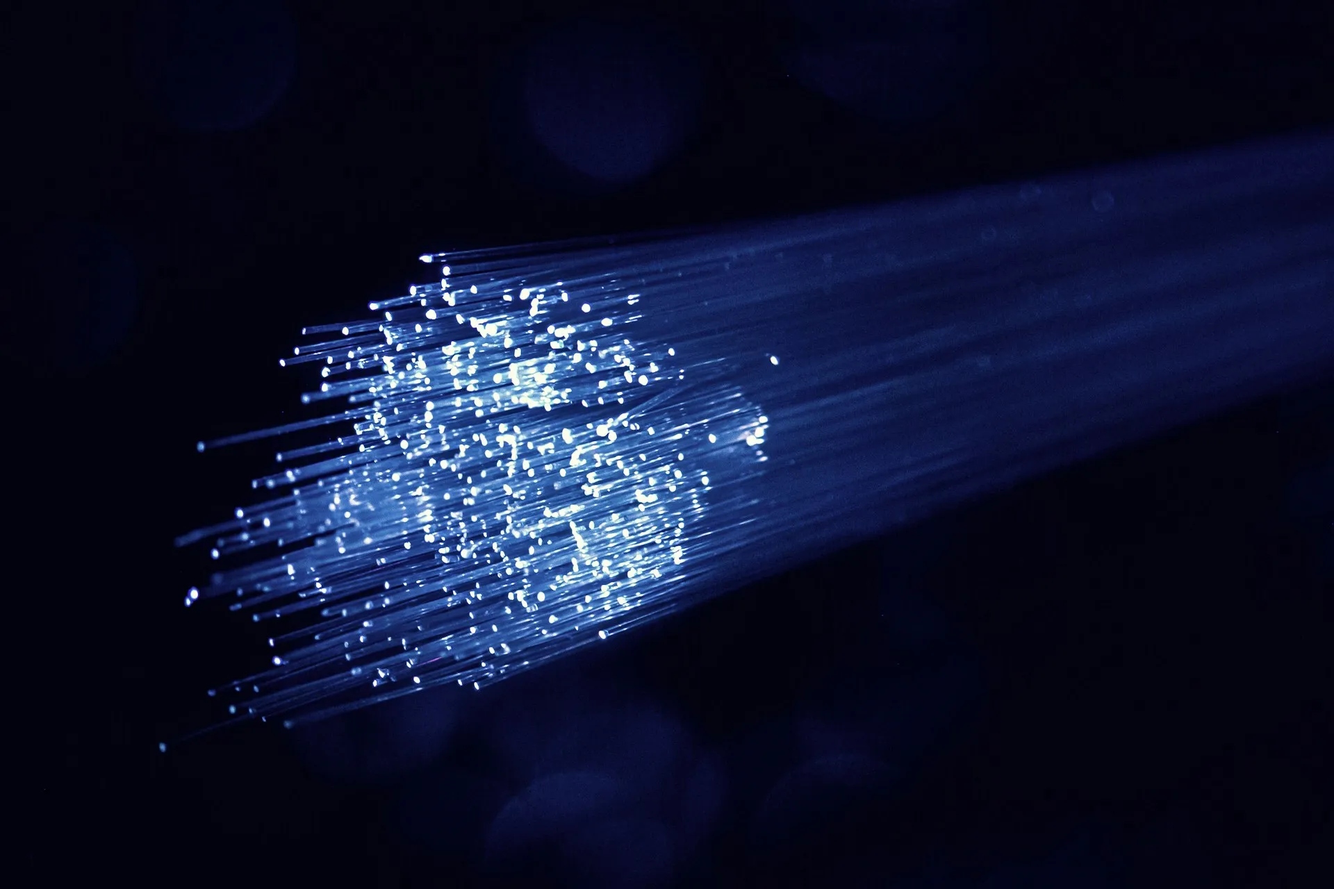 The mesh adds no new network. It runs over the links you already have, and adds routing that sends each event only where a subscriber wants it. Bundle of fibre optic strands glowing blue against a dark background
