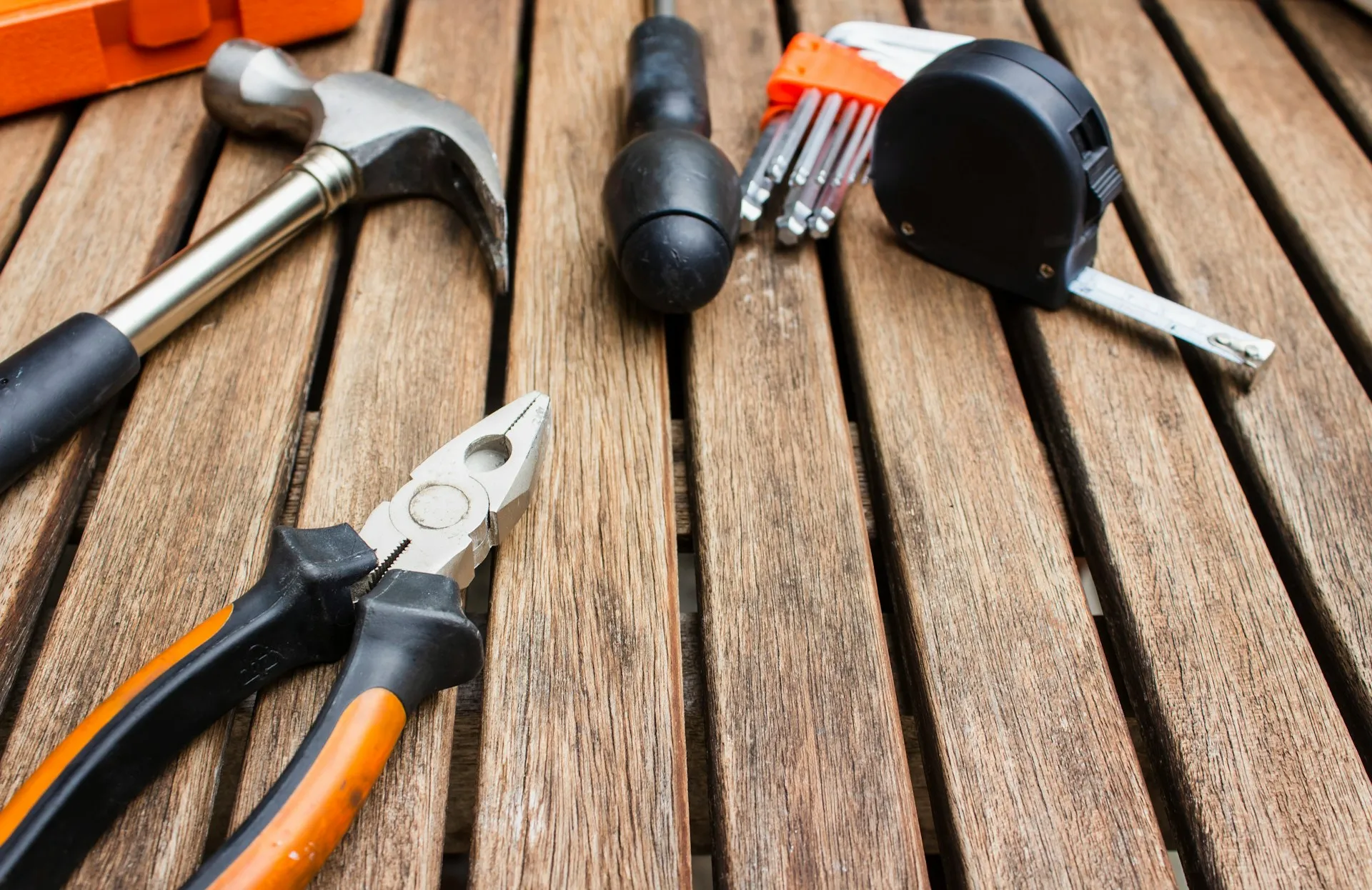 Nobody asks whether a hammer beats a screwdriver. A broker comparison is only useful once each layer of the architecture has a defined job. Hammer, pliers, screwdriver, hex keys and tape measure laid on a wooden slatted bench