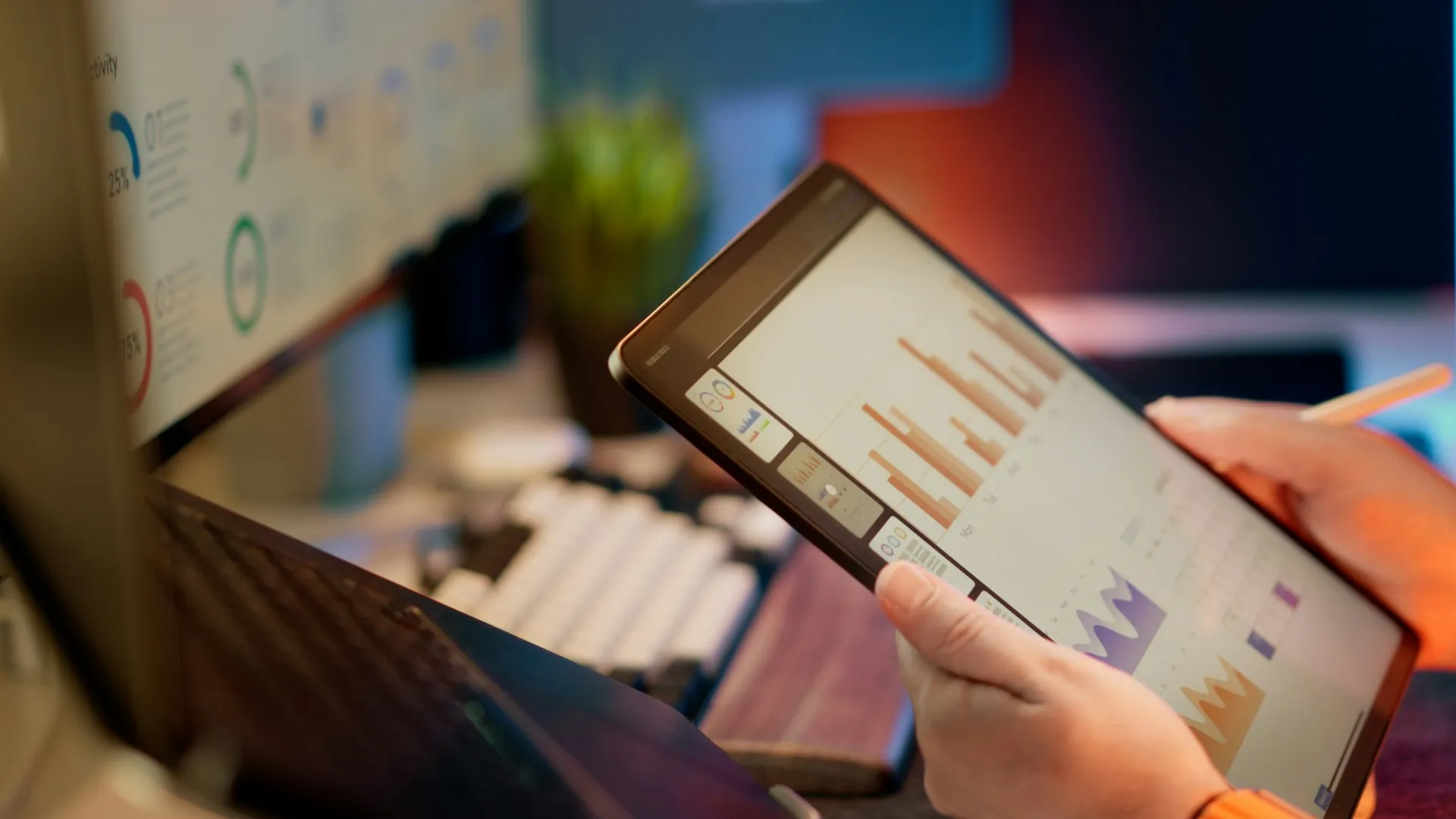 Most broker incidents announce themselves hours early as a trend: a queue that grows a little faster than it drains. Watching the slope is cheaper than restoring a line. Hands holding a tablet that shows bar and area charts beside a keyboard