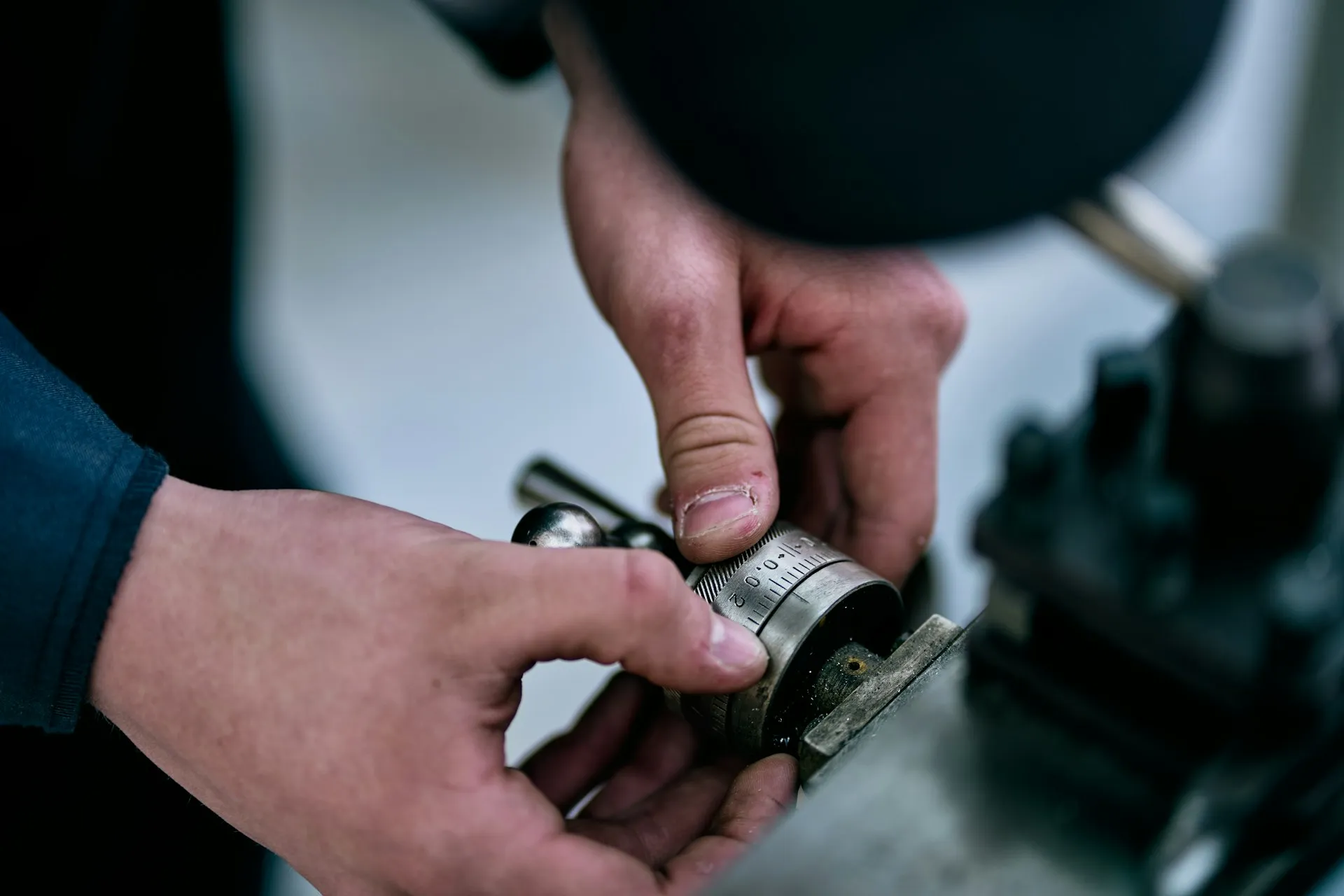 Check-out and check-in only work when every edit is made as deliberately as a setting on a dial: started from a known position, recorded, and reversible. Close-up of hands turning a graduated dial on a machine tool slide to set a precise position