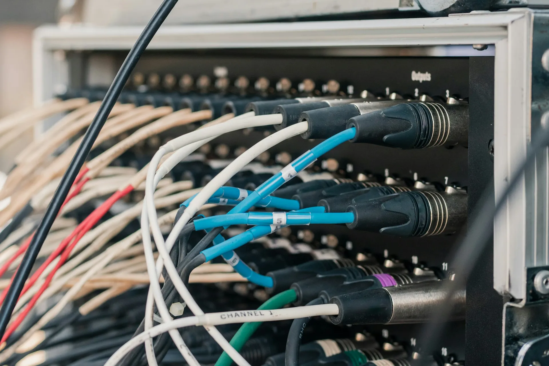A flat network is split one traced, labelled connection at a time, so production keeps running while each zone is cut over. Labelled blue and white cables plugged into the rear connectors of an equipment rack