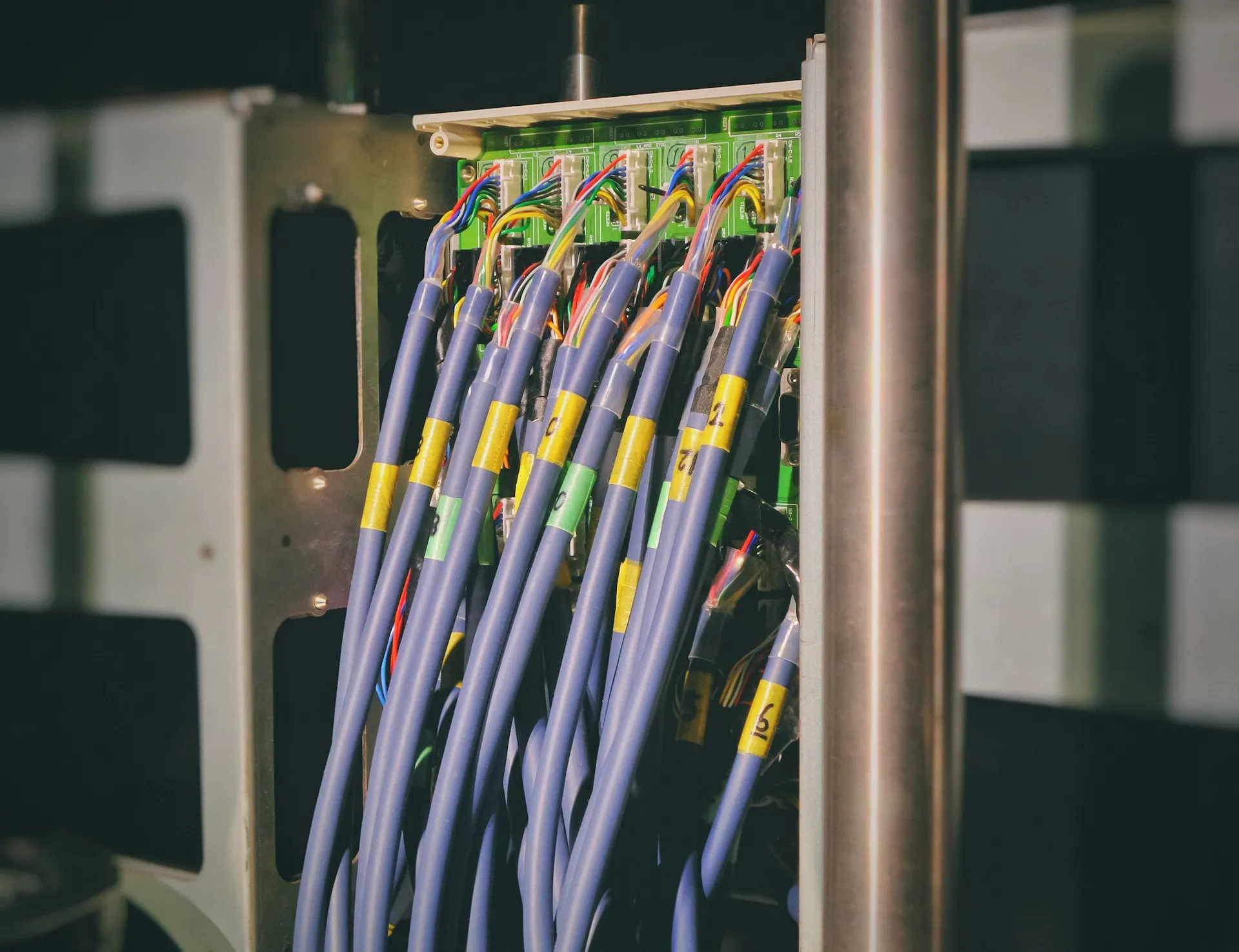 Numbered, sleeved cables terminated into connectors along a green circuit board inside a frame