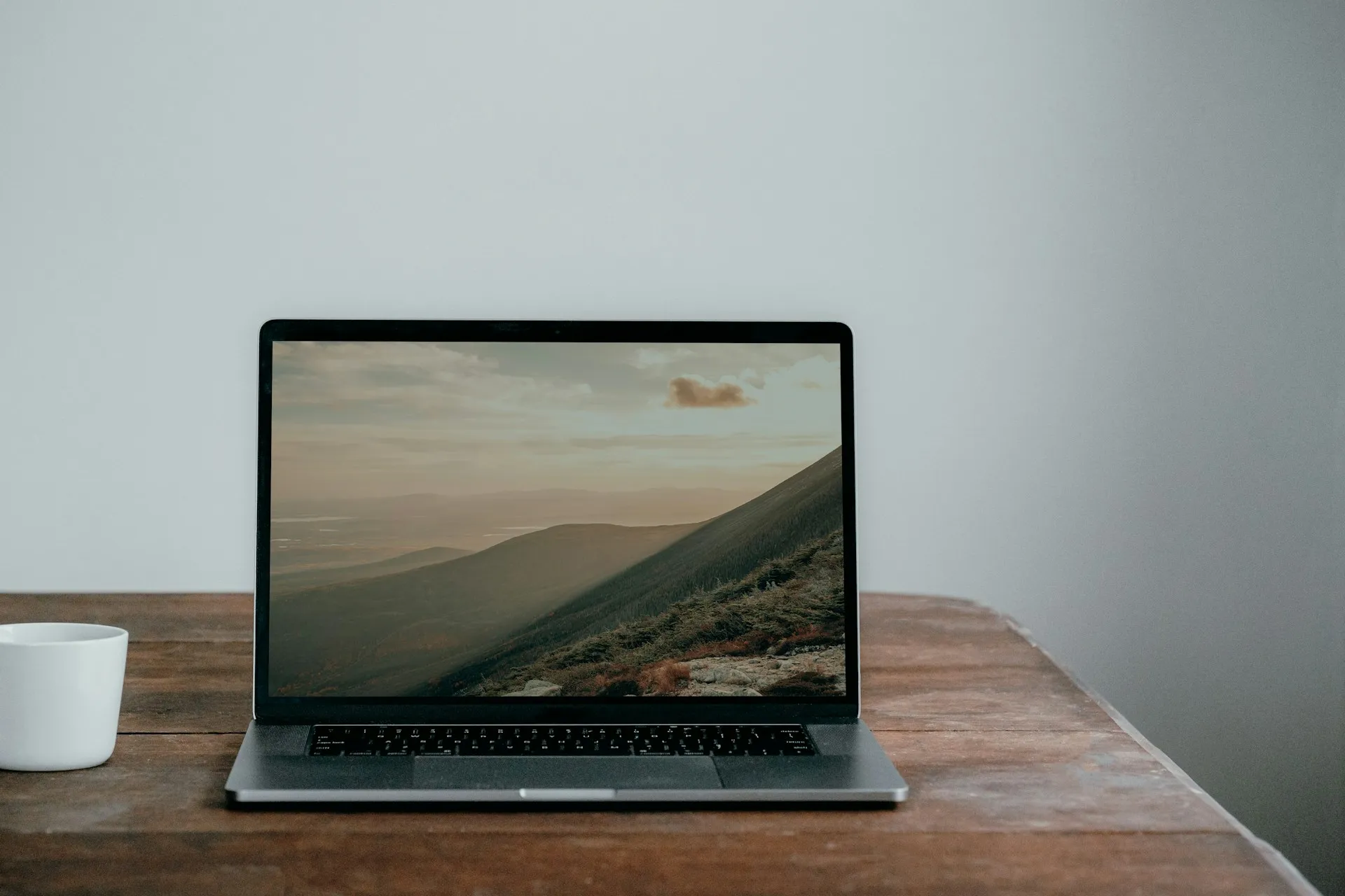 One laptop and the free desktop app are enough to prove an agent idea. The licence conversation starts when a team, real data and production arrive. Open laptop on a worn wooden desk beside a white mug against a plain grey wall