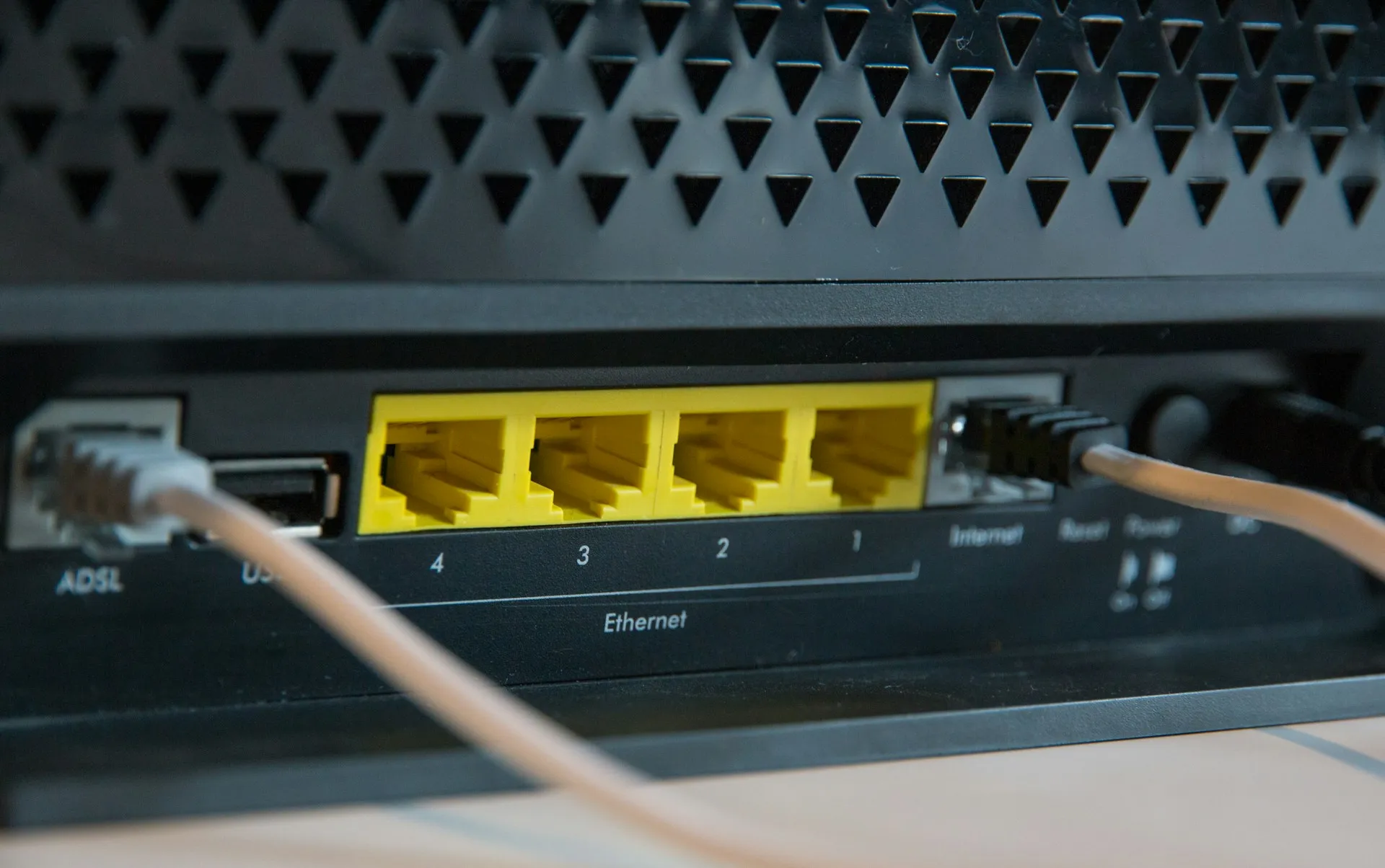 Edge gateways publish plant data into the first broker they meet, so that broker's MQTT and Sparkplug behaviour shapes everything above it. Close-up of a black network device with yellow ethernet ports and grey cables plugged in