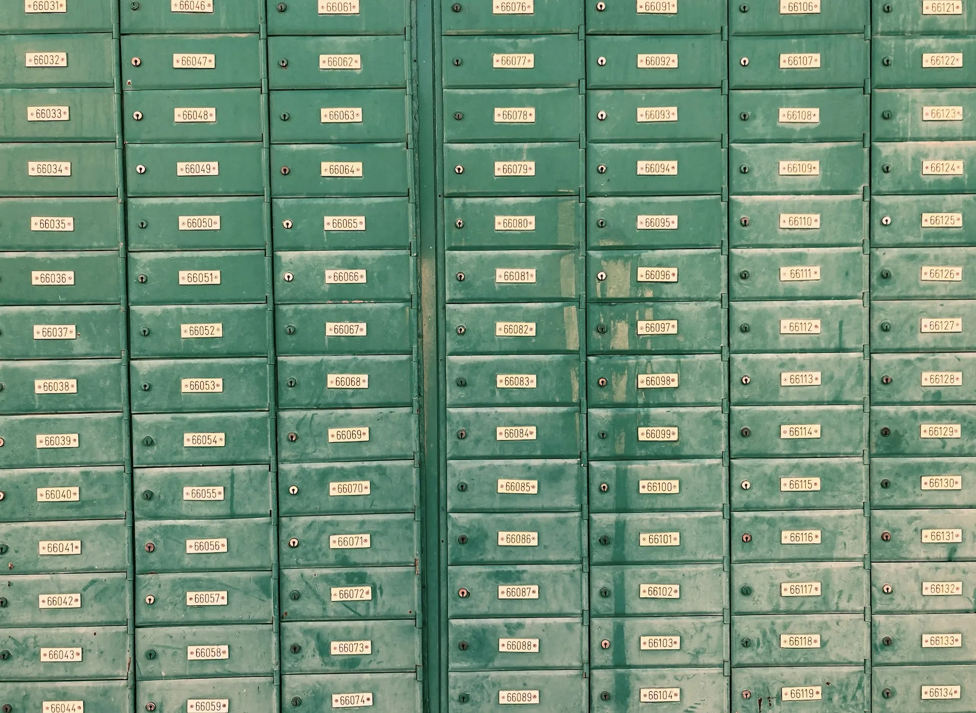 Each topic is an address, and a wildcard subscription collects from a whole row of boxes. The numbering scheme has to be agreed before the first letter is sent. Wall of green metal mailboxes, each with its own numbered label