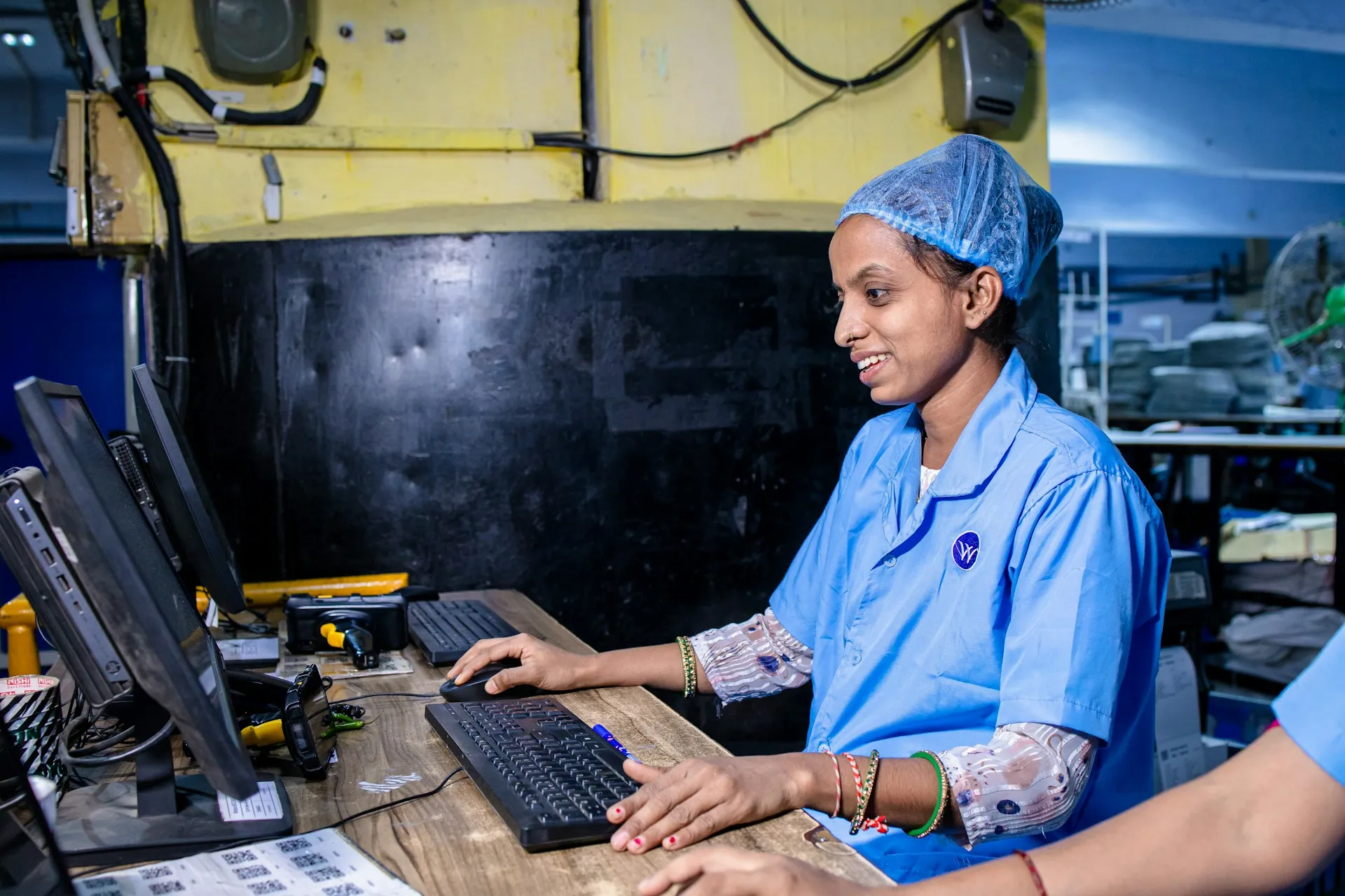 The supervisory layer needs the same backup and change history as the controllers beneath it, and since January 2026 the AutoSave variant that provided it is no longer supported. Operator in a hairnet using a desktop workstation with keyboard and monitors on a factory floor