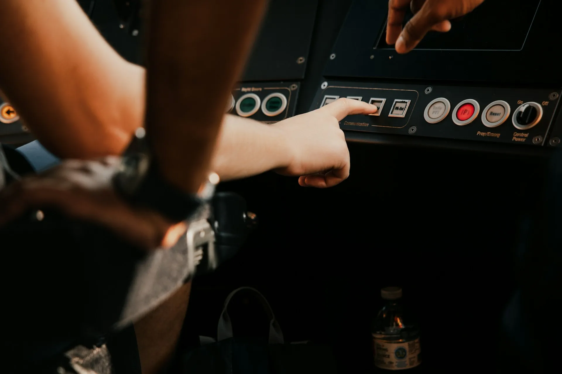 The same edit at the machine can be a planned fix, a slip or an unauthorised change. The job only reports that something moved; the plant's records decide which it was. A hand pressing a selector button on a dark machine operator panel beside red and white pushbuttons