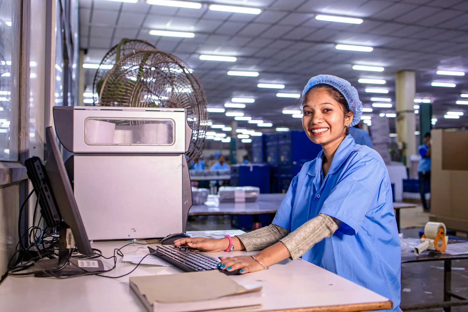 Manufacturing reuses the patterns banks and retailers proved: fan-out of master data, guaranteed production orders and many sites linked to the centre. An operator smiling at a computer workstation on a busy factory production floor