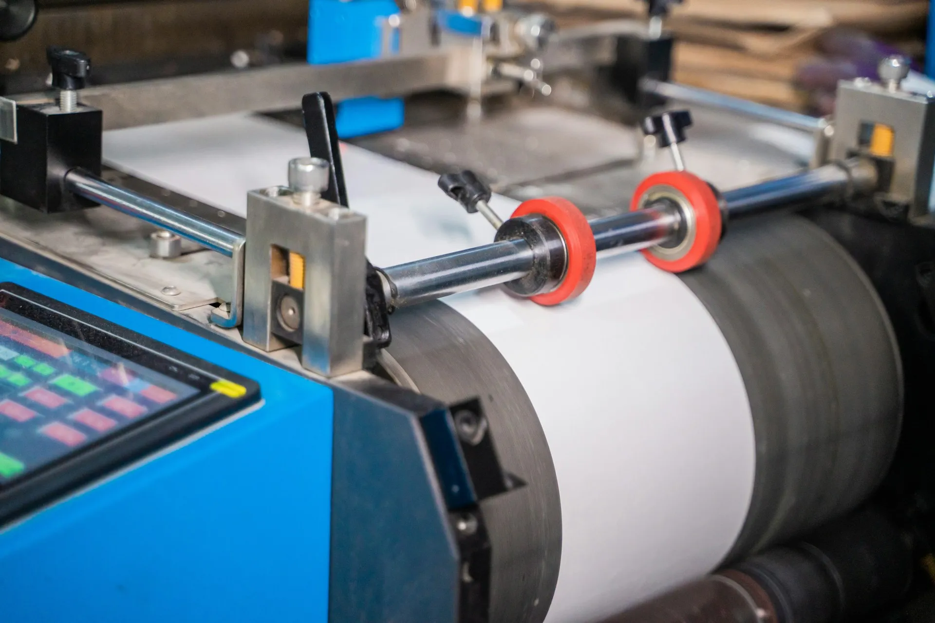 Paper web running over rollers on a converting rewinder with an operator touchscreen beside it