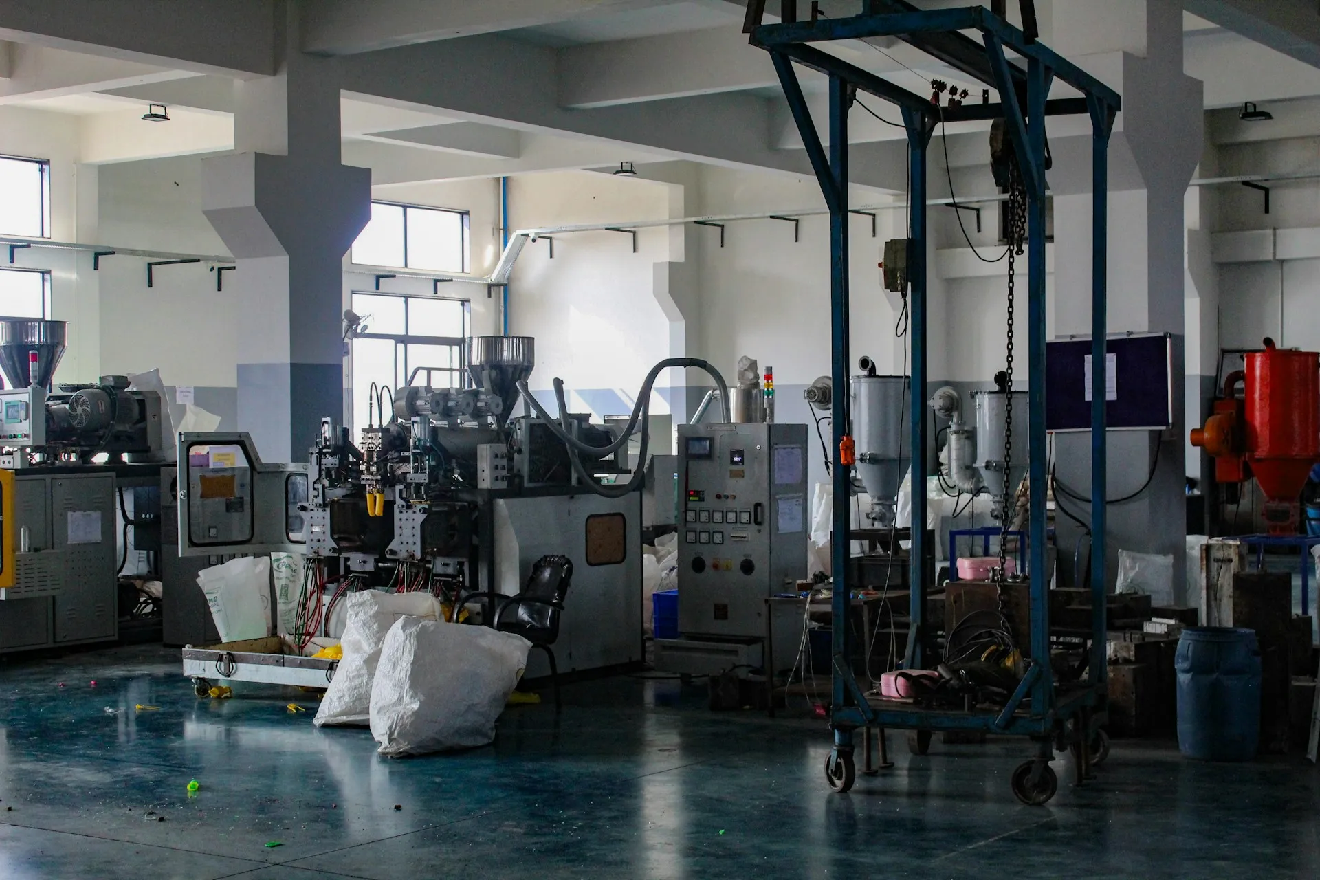 One hall, many vendors and many ages of control system: none of them can be imaged, patched or restarted on an IT schedule. Plastics moulding plant floor with several machines, control cabinets, hoppers and sacks of material