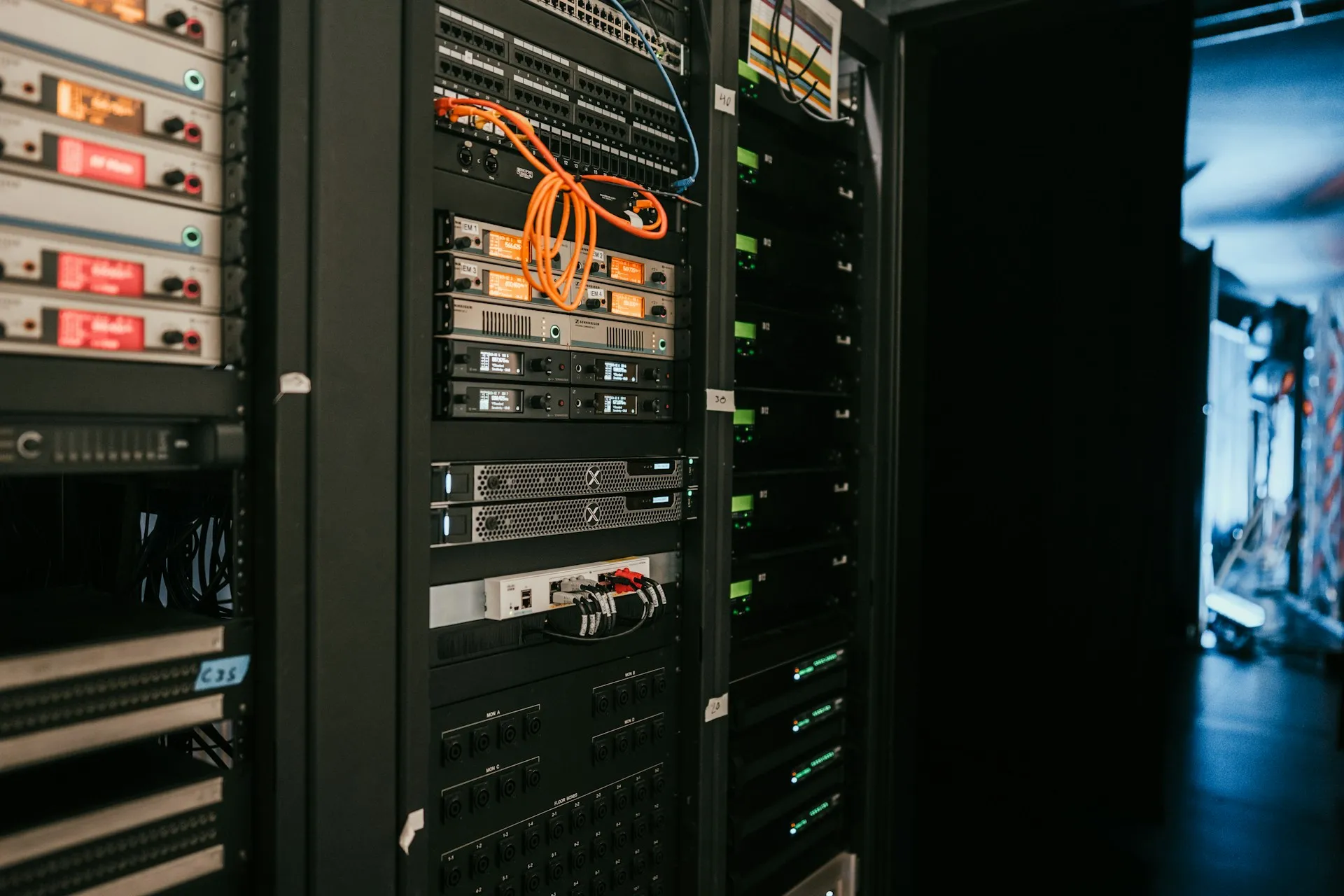 Each agent and server connection becomes a firewall rule on gear like this, so design the octoplant layout with the network team, not after them. Dimly lit equipment racks with patch panels, orange patch cables and status lights