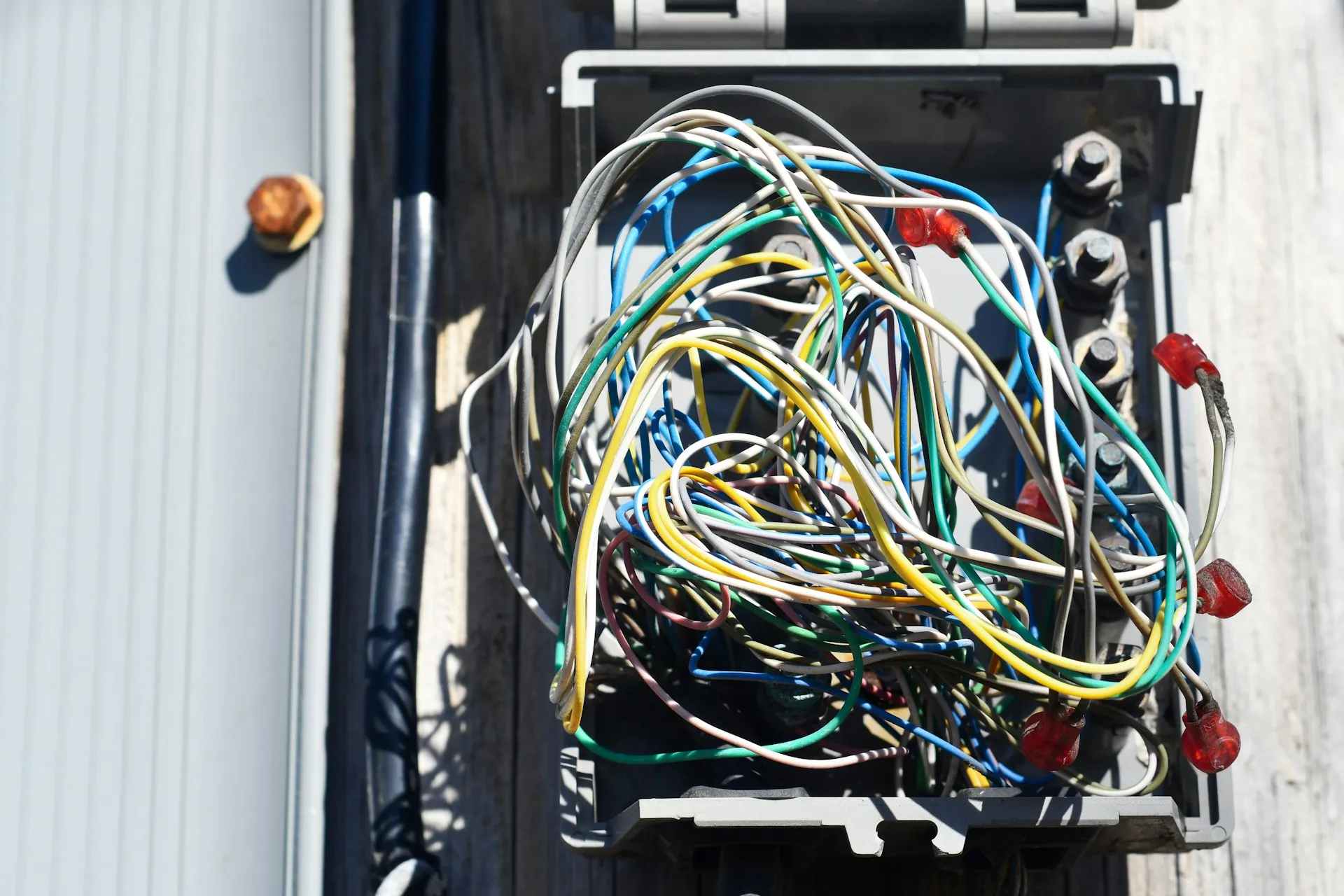 On a fieldbus, the fault is usually in the copper: a termination, a splice or a second ground point, long before it is in the controller. Open outdoor junction box with a tangle of coloured conductors and crimped terminals
