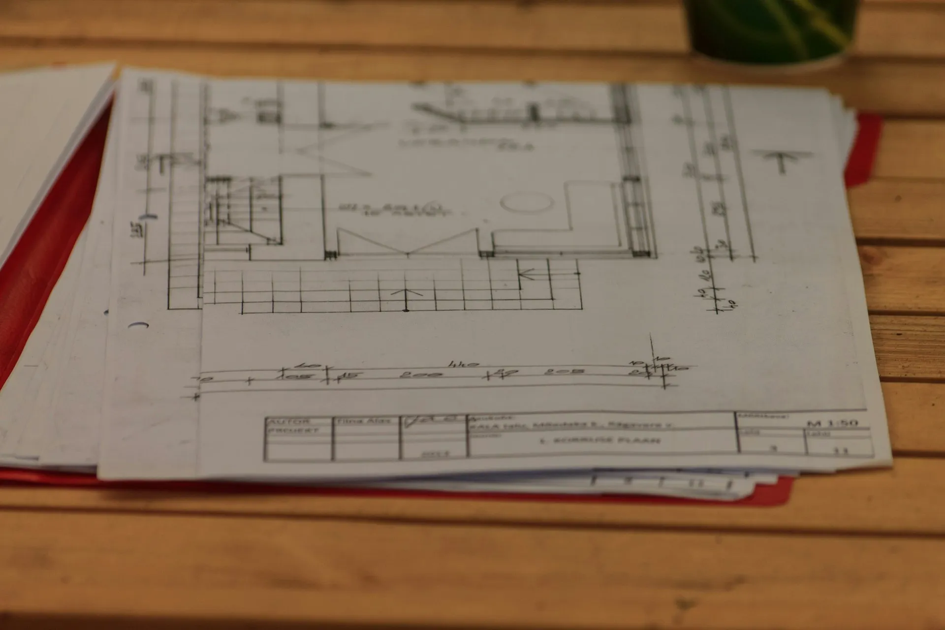 Most plants already document interfaces, but in drawings, spreadsheets and email. A catalogue entry is worth having only if it replaces that paperwork rather than adding to it. Stack of printed technical drawings and documents spread on a wooden desk
