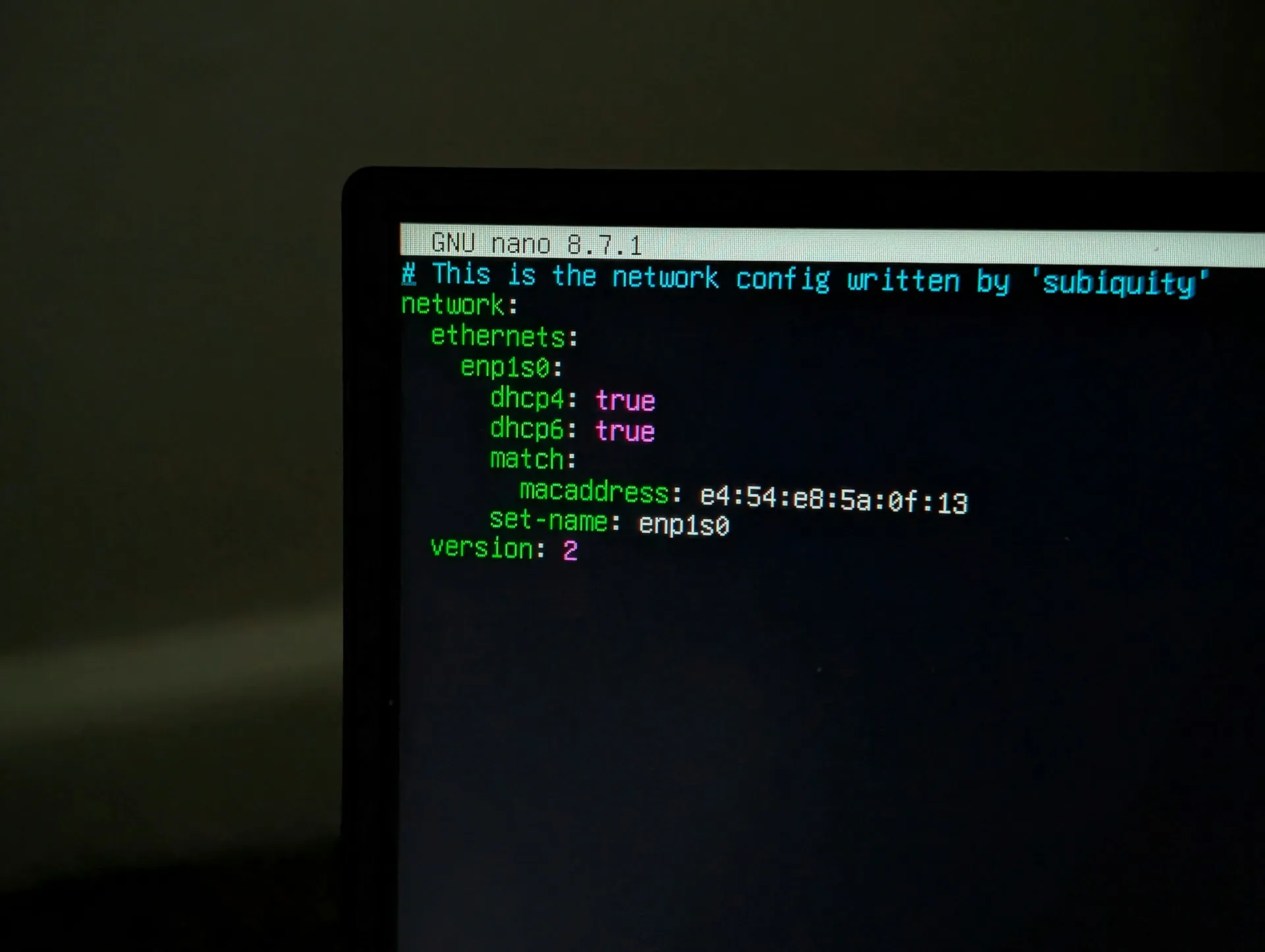 Day to day, the difference between brokers is felt in configuration and tooling: exchanges and plugins on one side, topics, VPNs and a mesh on the other. Laptop screen showing a network configuration file open in a terminal text editor in a dark room