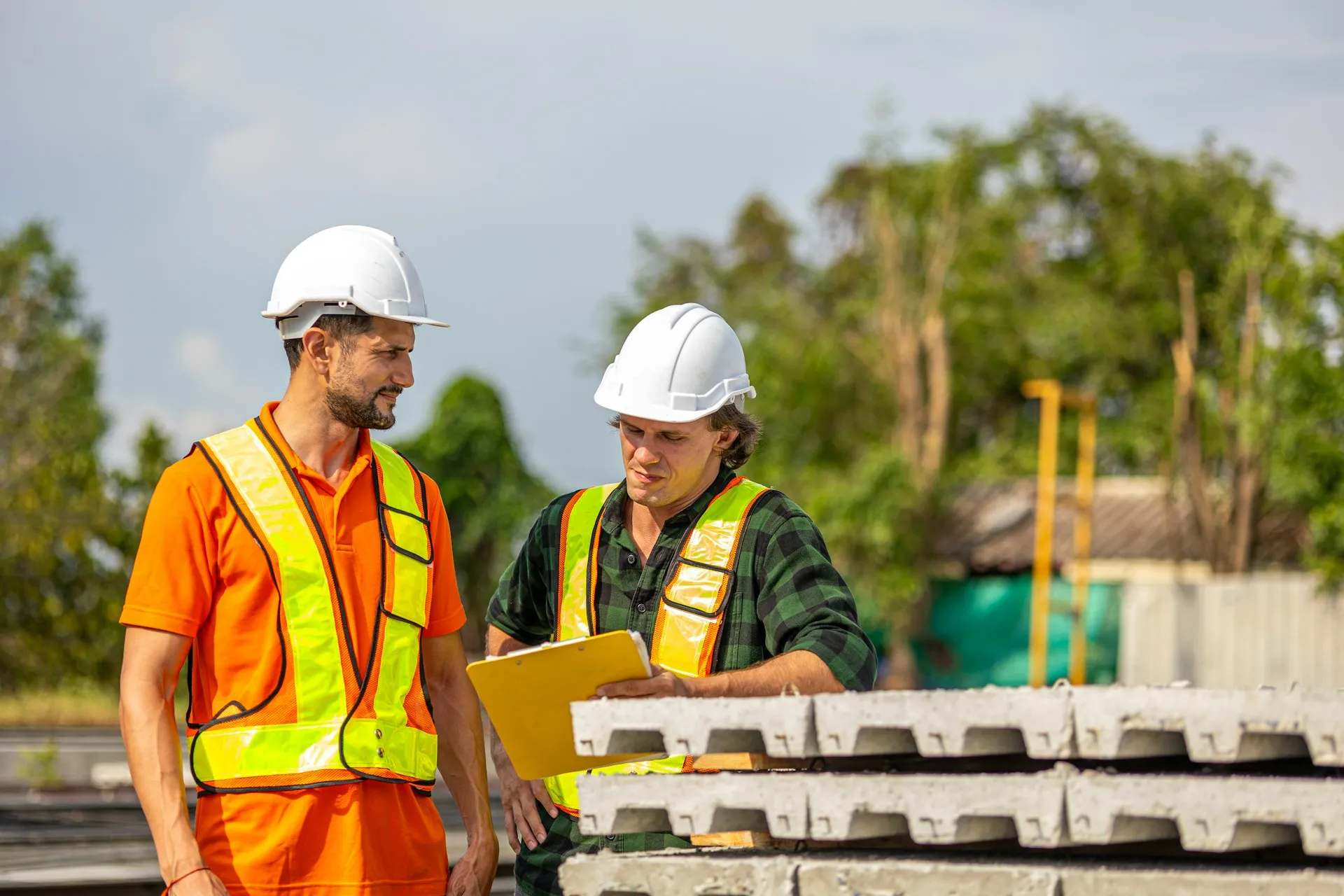 An integrator earns its fee on site, agreeing topic names, failover tests and ownership with the plant team, not in the licence quote. Two engineers in white hard hats and high-visibility vests reviewing a clipboard on an outdoor site