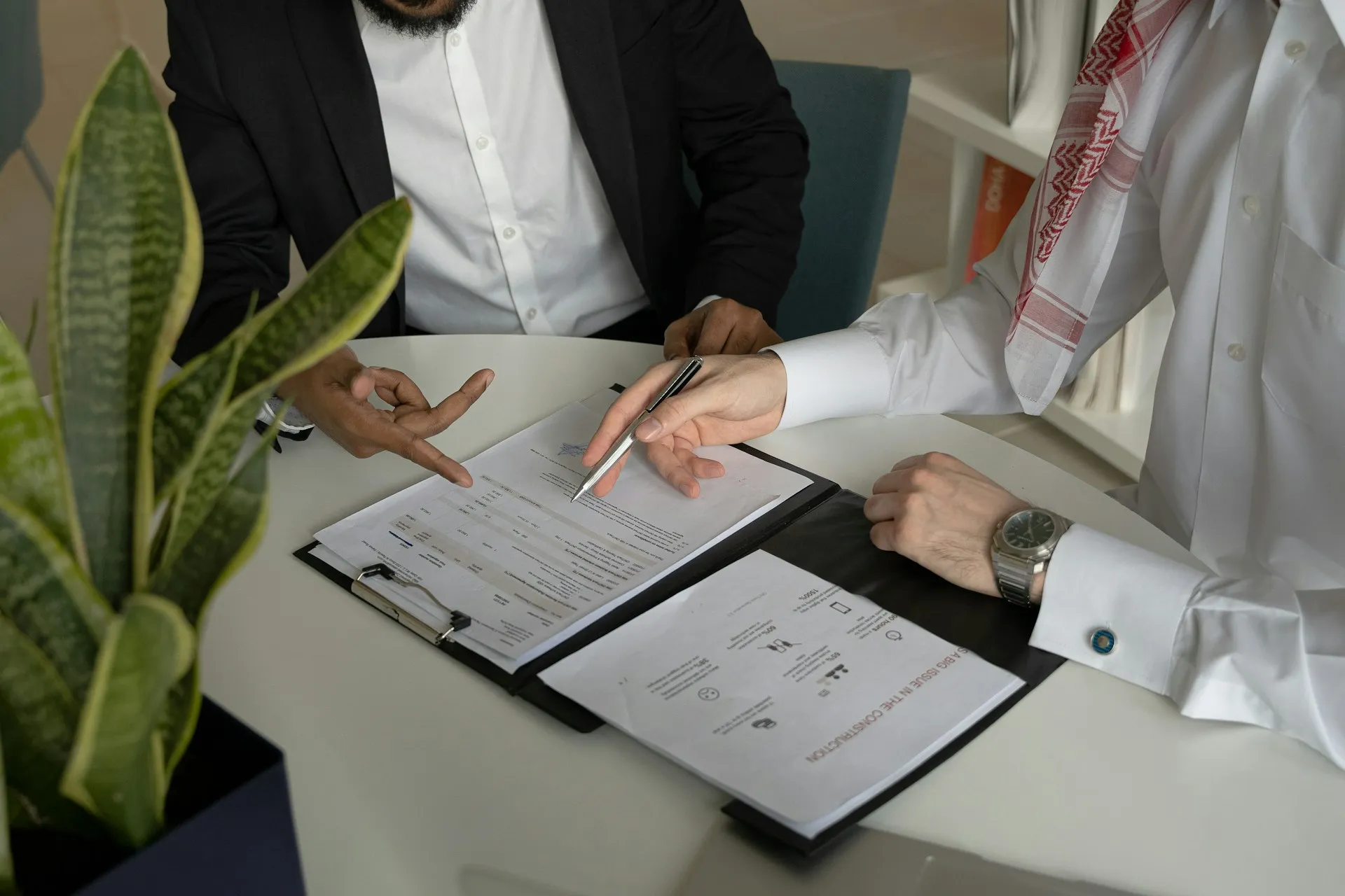 The partner who signs the order is usually the one who answers the phone during a failed restore, so the support clause matters more than the discount. Two people at a round table reviewing a printed agreement, one pointing at a clause with a pen