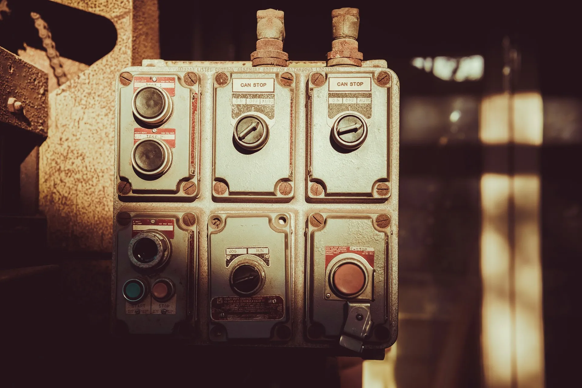 The clock that matters runs from the moment someone presses stop to the moment the line starts again, and the restore itself is only a few minutes of it. Weathered industrial pushbutton station with start, stop and selector switches in warm light