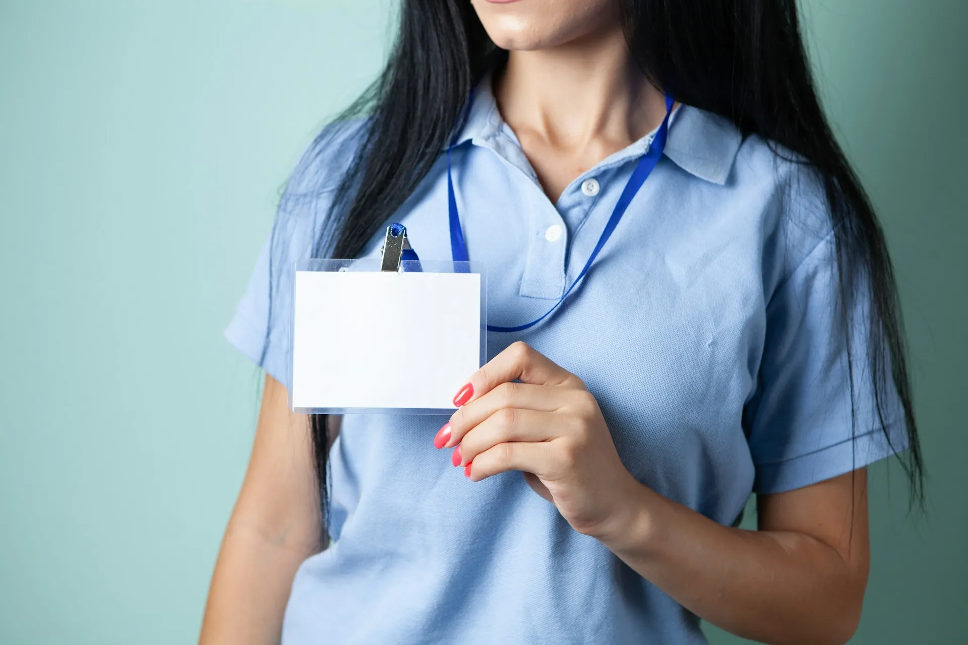 A badge decides who enters the building and which doors it opens. Client authentication and ACLs do the same for every application on the broker. Person in a blue work shirt holding a blank white identification badge on a lanyard