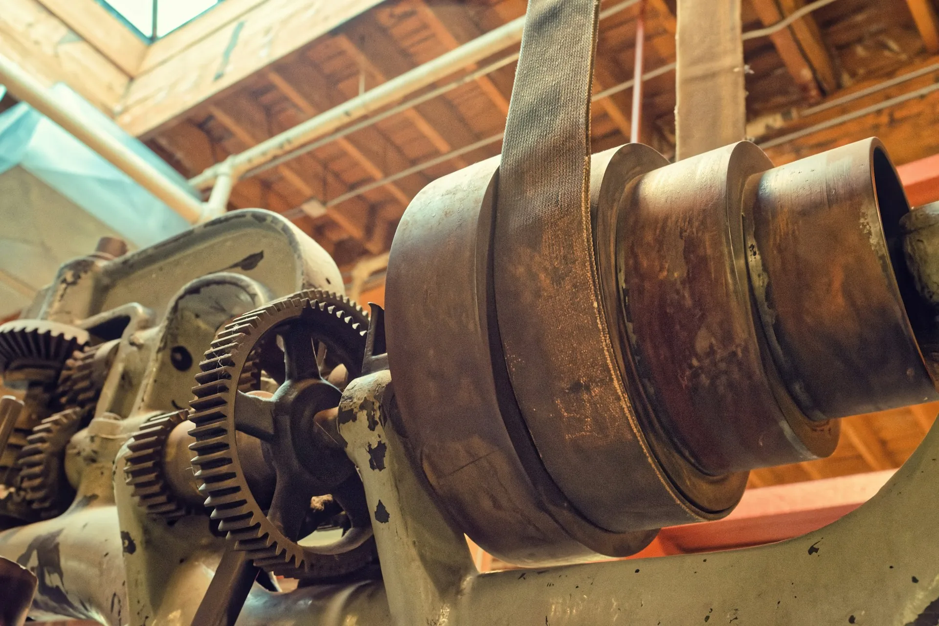 Many drive and motion faults start in the mechanics the drive is turning. A slipping belt or worn gear reaches the drive as overcurrent or following error, and replacing the drive changes nothing. Worn flat belt over a rusted pulley driving exposed gears on an old industrial machine